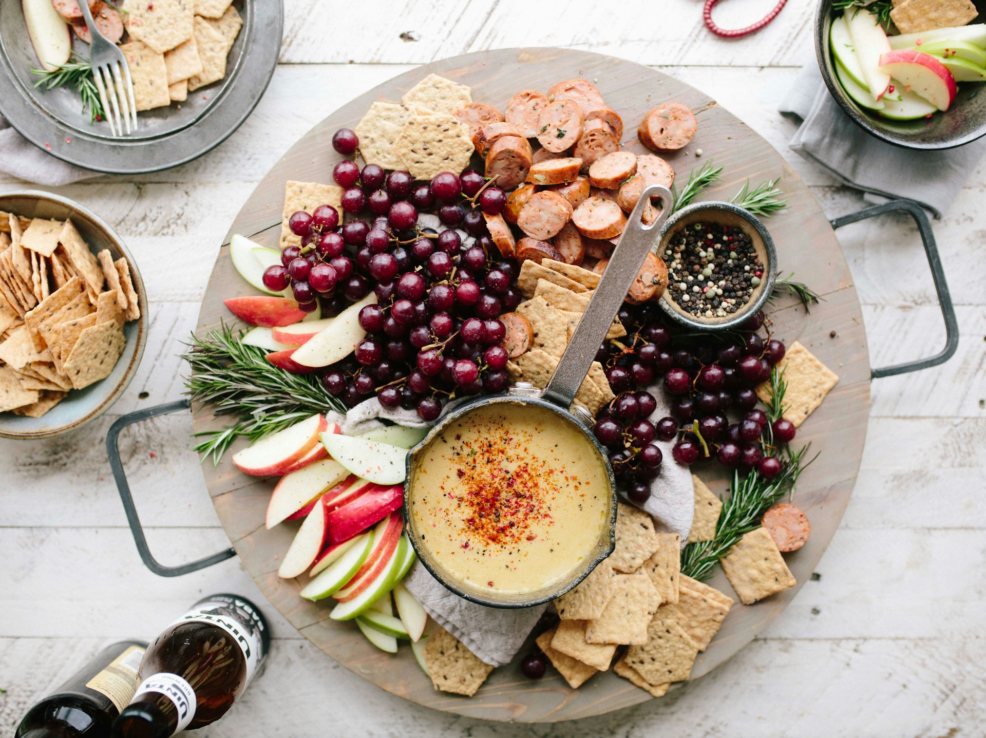 A rustic grazing board with fruit, crackers, herbs and warm dip